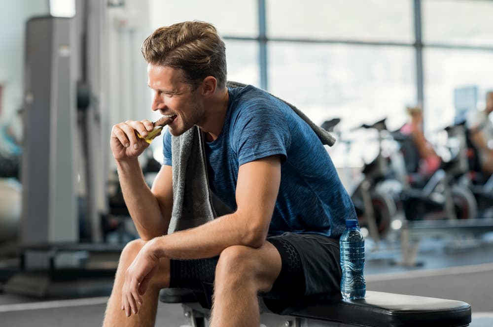Man eating energy bar at gym after a workout