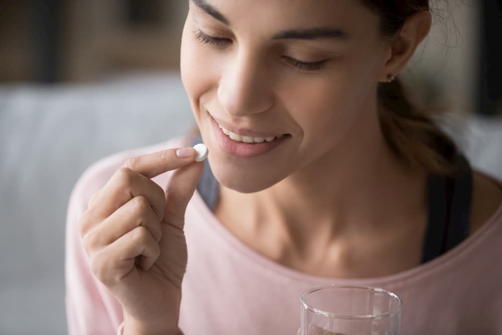 Close up of woman taking probiotic tablet.